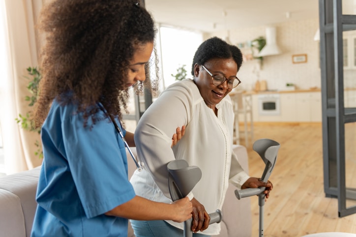Older woman using walkers with the help of a nurse in a long-term care facility in Monroe, LA